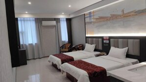 A hotel room with two beds, a desk, a chair, and a large window with curtains.
