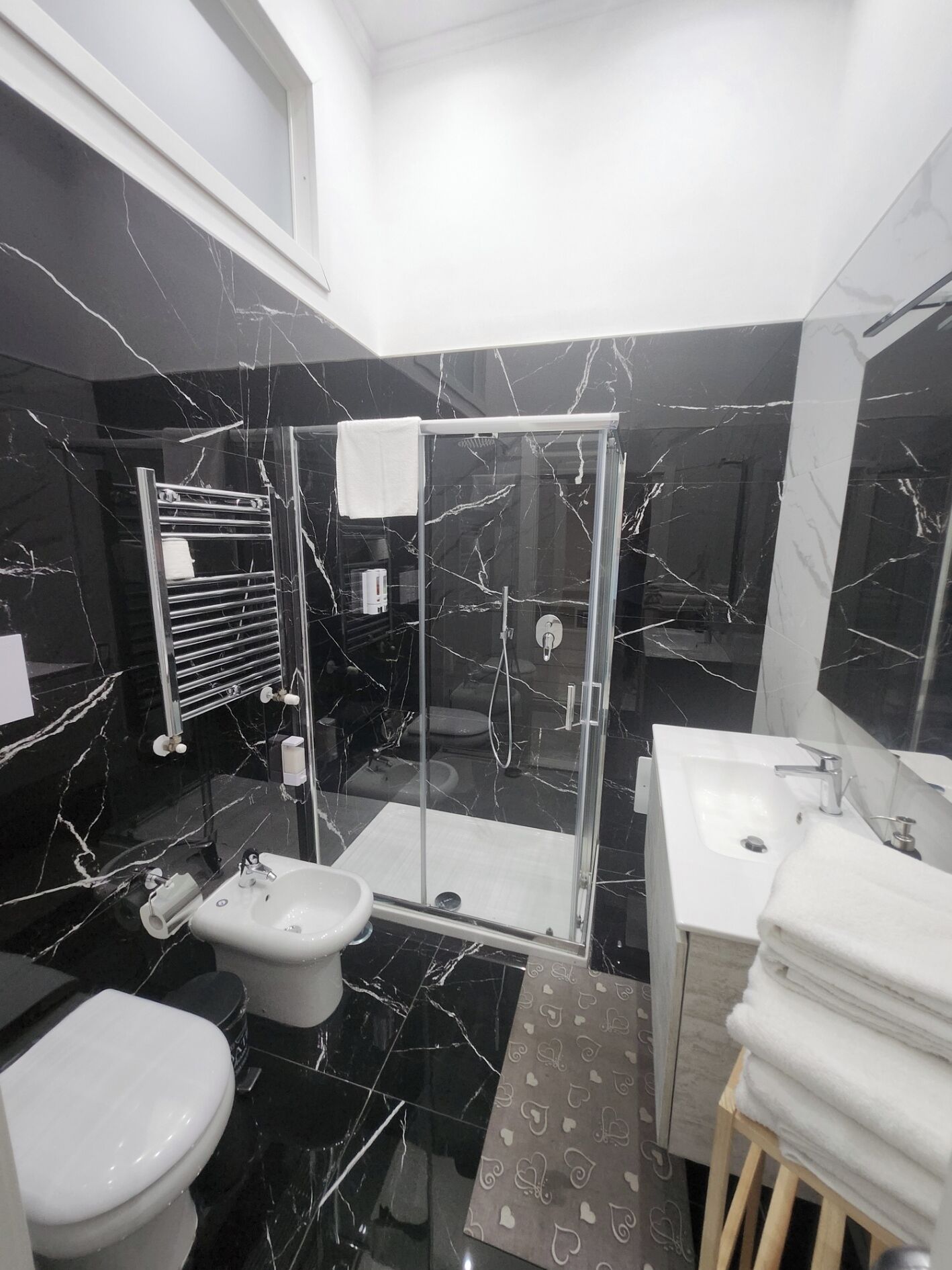 Un baño moderno con ducha de vidrio, lavamanos blanco y retrete.