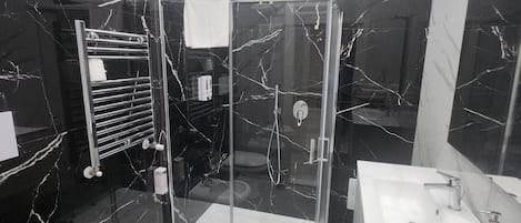 Un baño moderno con ducha de vidrio, lavamanos blanco y retrete.