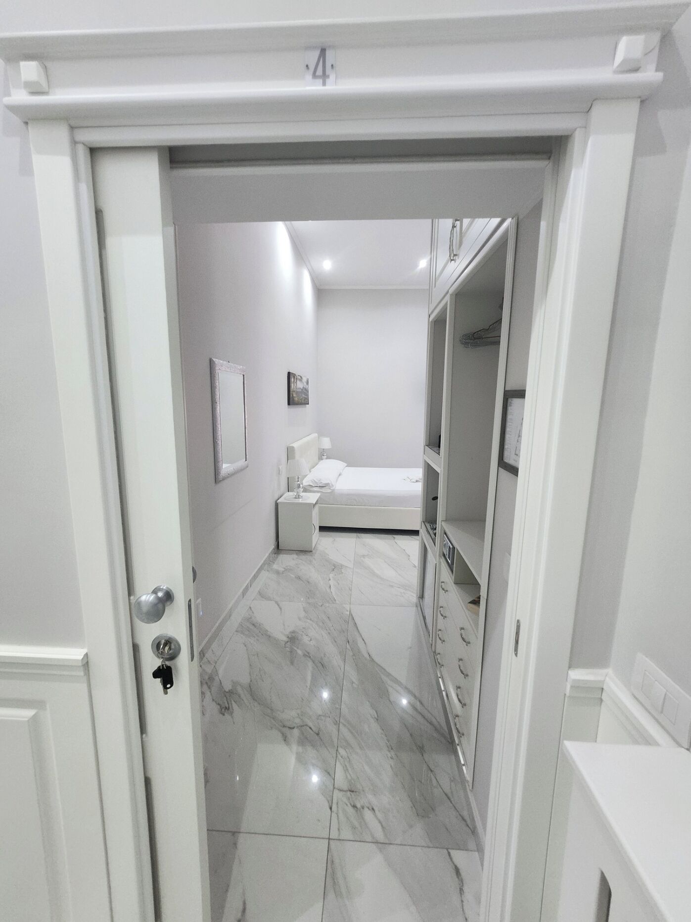 Een moderne badkamer met een marmeren vloer, een witte wastafel en een spiegel.