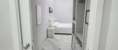 Een moderne badkamer met een marmeren vloer, een witte wastafel en een spiegel.