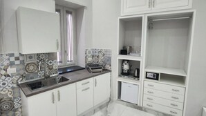 A modern kitchen with white cabinets, a marble countertop, and a built-in oven.