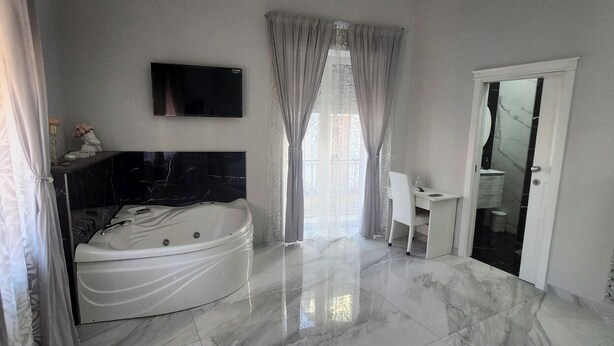 A spacious bedroom with a large bed, a built-in TV, and a bathroom with a mirror and toilet.