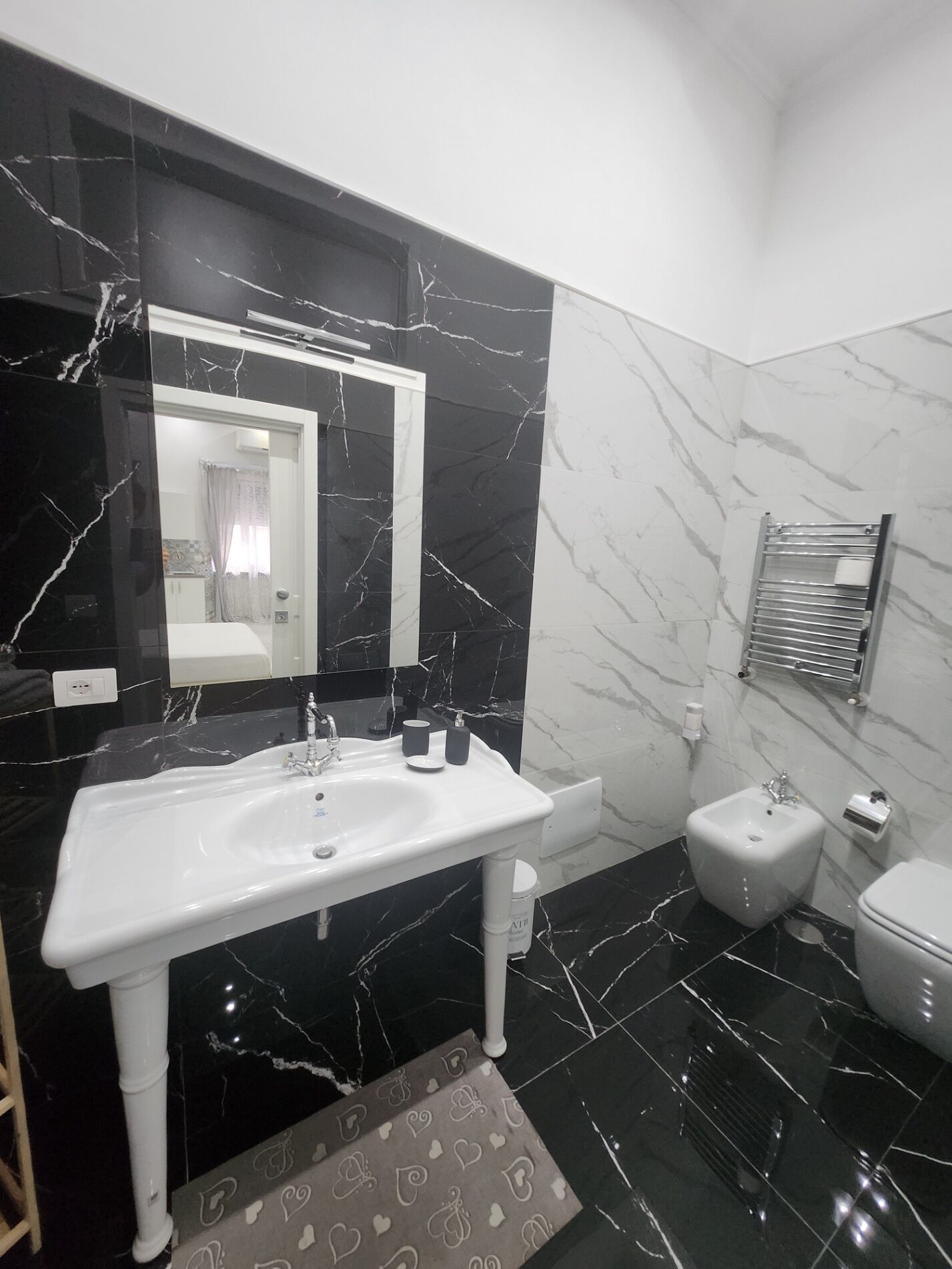 Une salle de bain avec un lavabo blanc, un miroir, des toilettes et un porte-serviettes.