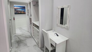 A hallway with a white desk, a mirror, and a wardrobe.