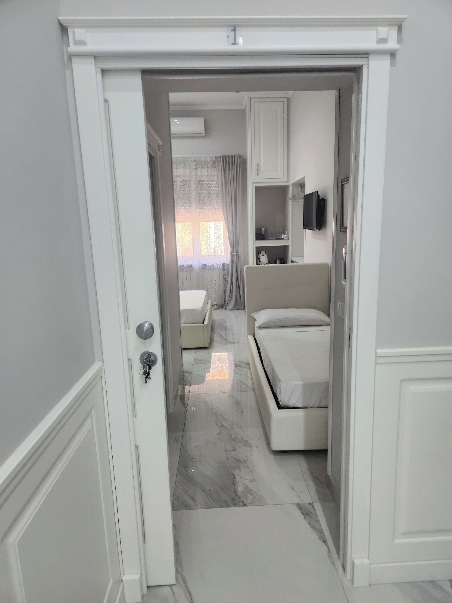 Un dormitorio con cama, sofá y televisor en la pared.