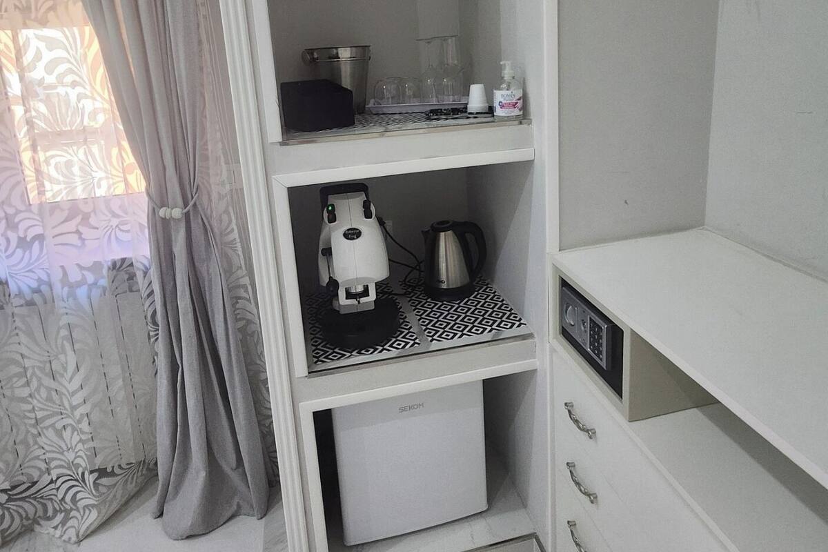 A compact, well-organized bathroom with a shower, a toilet, and a sink. There is a towel rack and a small shelf with toiletries.