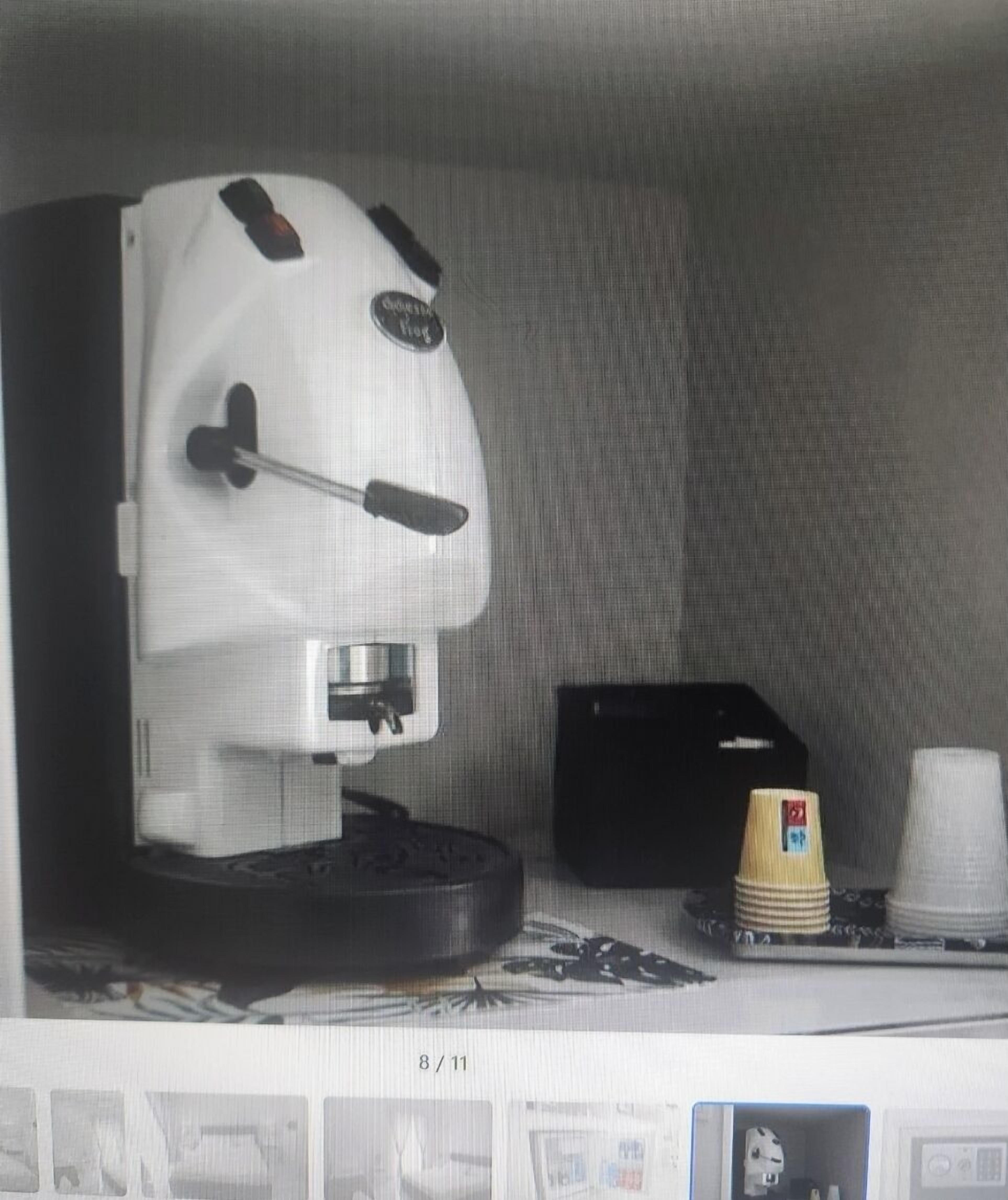 A coffee machine, a black box, and stacked paper cups on a counter.