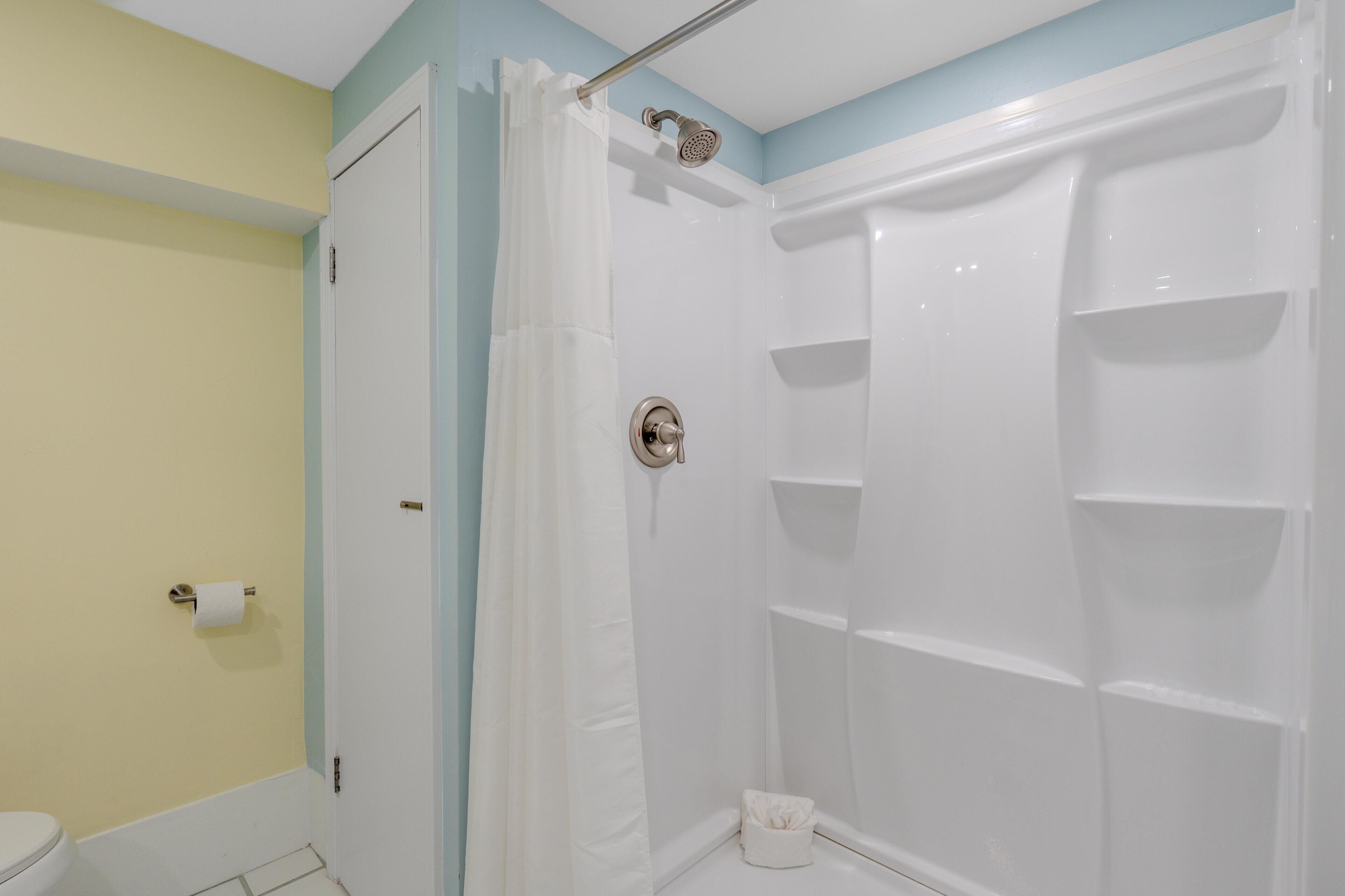 Une salle de bain avec une cabine de douche blanche, des toilettes et un porte-serviettes.