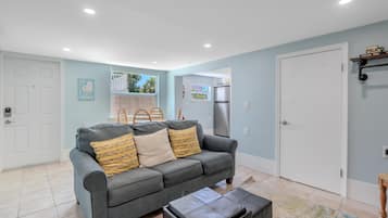 A living room with a grey sofa, a small table, and a door.