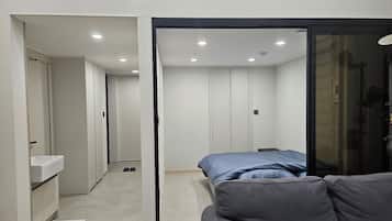 A modern bedroom with a bed, a sofa, and a bathroom with a sink.