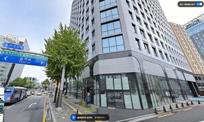 Un edificio moderno con ampie finestre e facciata in vetro, situato accanto a una strada con cartelli indicatori.