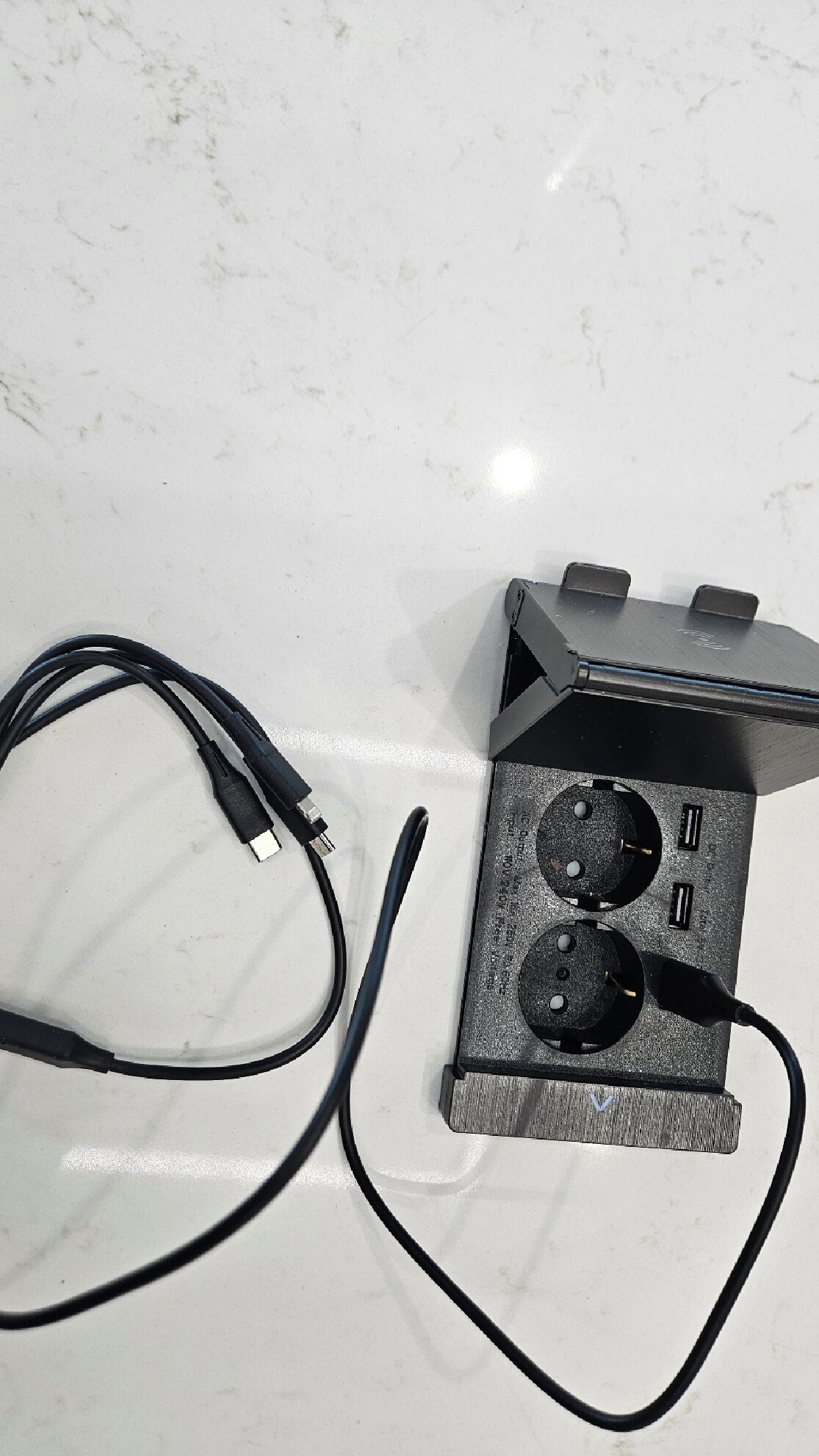 A power strip with two outlets and a USB port, connected to a black cable.
