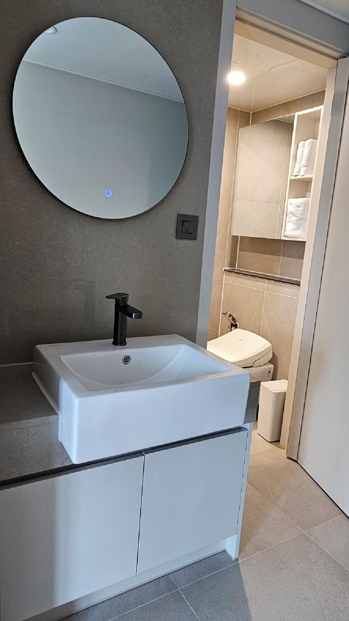 A modern bathroom with a white sink, black faucet, and a large mirror.