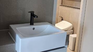 A modern bathroom with a white sink, black faucet, and a large mirror.