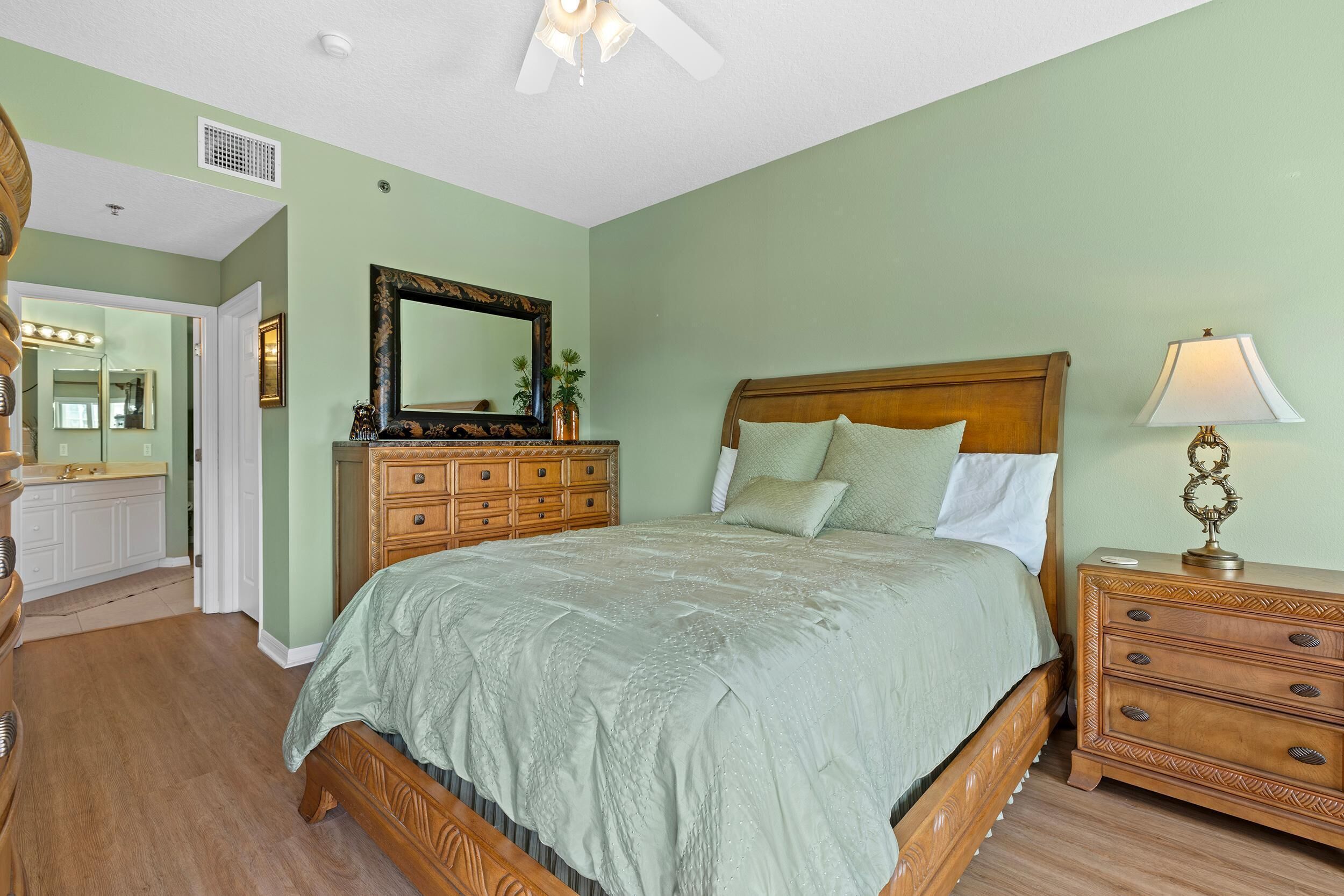A bedroom with a bed, dresser, nightstand, and a mirror.