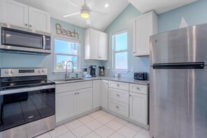 A modern kitchen with stainless steel appliances, white cabinetry, and a ceiling fan. - Island Paradise Estate (Fort Myers Beach)