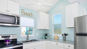 A modern kitchen with white cabinets, a stainless steel refrigerator, a microwave, and a kettle. - Island Paradise Estate (Fort Myers Beach)