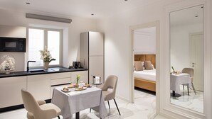 Una habitación de hotel moderna con kitchenette, zona de comedor y cama.