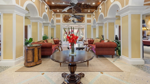 A spacious lobby with a round dining table, red sofas, and a decorative ceiling fan. - Minorca Paros 402 (New Smyrna Beach)