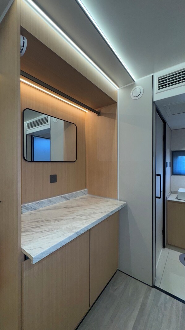 A modern bathroom with a wooden vanity, a mirror, and a built-in shower area.