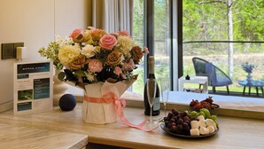 A modern kitchen with a large window, a vase of flowers, a bottle of champagne, and a fruit bowl. - Space Camp (Interlachen)