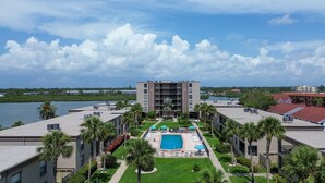 Un hôtel doté d’une cour intérieure avec une piscine, entourée de palmiers et offrant une vue sur un lac.