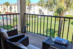 Relax on the balcony with a refreshing drink, taking in the serene views of the lush lawn and palm trees.