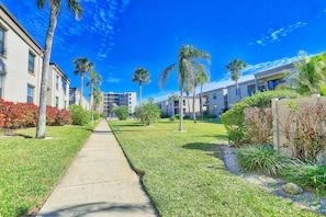 Stroll through a serene, lush green space, surrounded by modern buildings with clean lines and balconies.