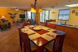 Relax in this open-plan living space with a dining table for four, sofa, and TV.
