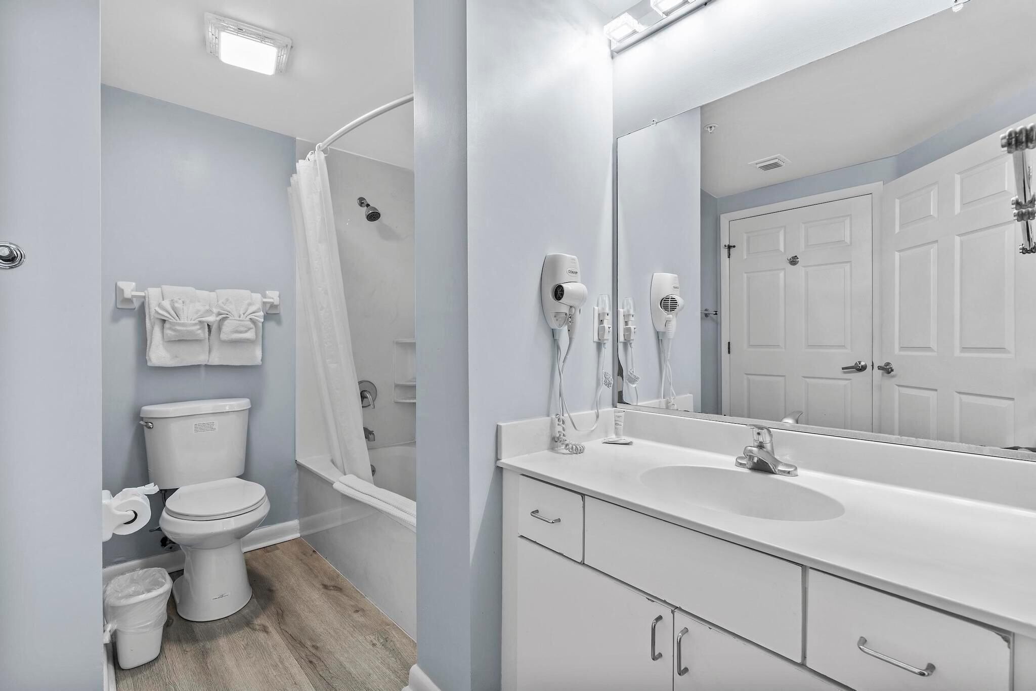 A modern bathroom with a shower, toilet, and a large mirror above the sink.