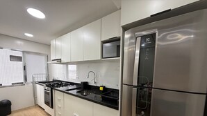 Une cuisine moderne dotée d’appareils électroménagers en acier inoxydable, de meubles blancs et d’un plan de travail noir.