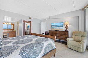 A bedroom with a bed, a TV, a chair, and a dresser. - Surfside Club 503 (Daytona Beach Shores)