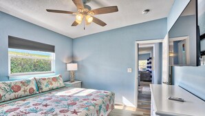 Une chambre à coucher avec un lit, un ventilateur de plafond, une fenêtre et une commode.