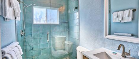 Ein Badezimmer mit Glasdusche, Toilette, Waschbecken und Spiegel.