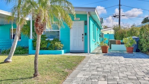 Un bâtiment turquoise avec une porte blanche, portant le numéro 453, et une allée pavée.