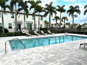 Relax by the rectangular pool surrounded by lounge chairs and palm trees.