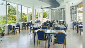 A spacious restaurant with high ceilings, large windows, and modern furniture. - Rehendhi Villa (Maafushi)