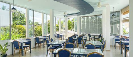 Un restaurante espacioso con techos altos, ventanas amplias y mobiliario moderno.