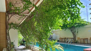 A poolside area with a wooden deck, seating, and a sign indicating a no-shoe policy. - Rehendhi Villa (Maafushi)