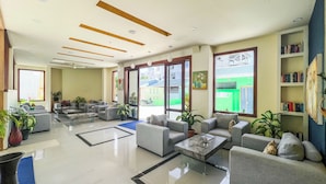 A spacious lobby with multiple seating areas, a coffee table, and a bookshelf. - Rehendhi Villa (Maafushi)