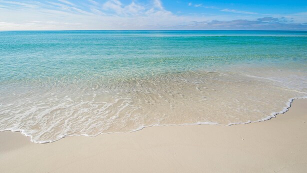 A beach with clear turquoise water and a sandy shore.
