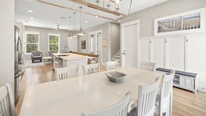 Une cuisine spacieuse dotée d’un grand îlot central, de meubles blancs et de luminaires suspendus.