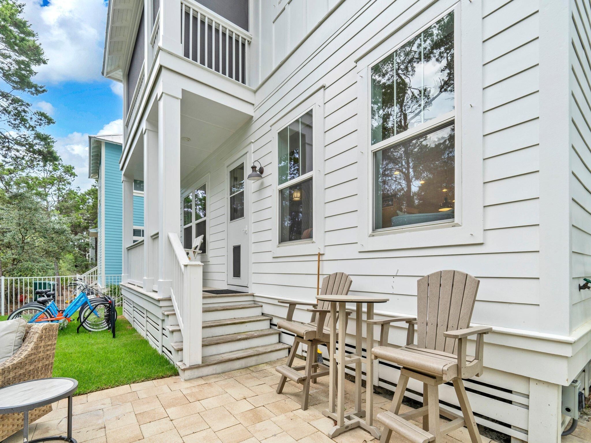 A white house with a porch, outdoor seating, and bicycles.