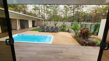 A backyard with a swimming pool, outdoor seating, and a garden.