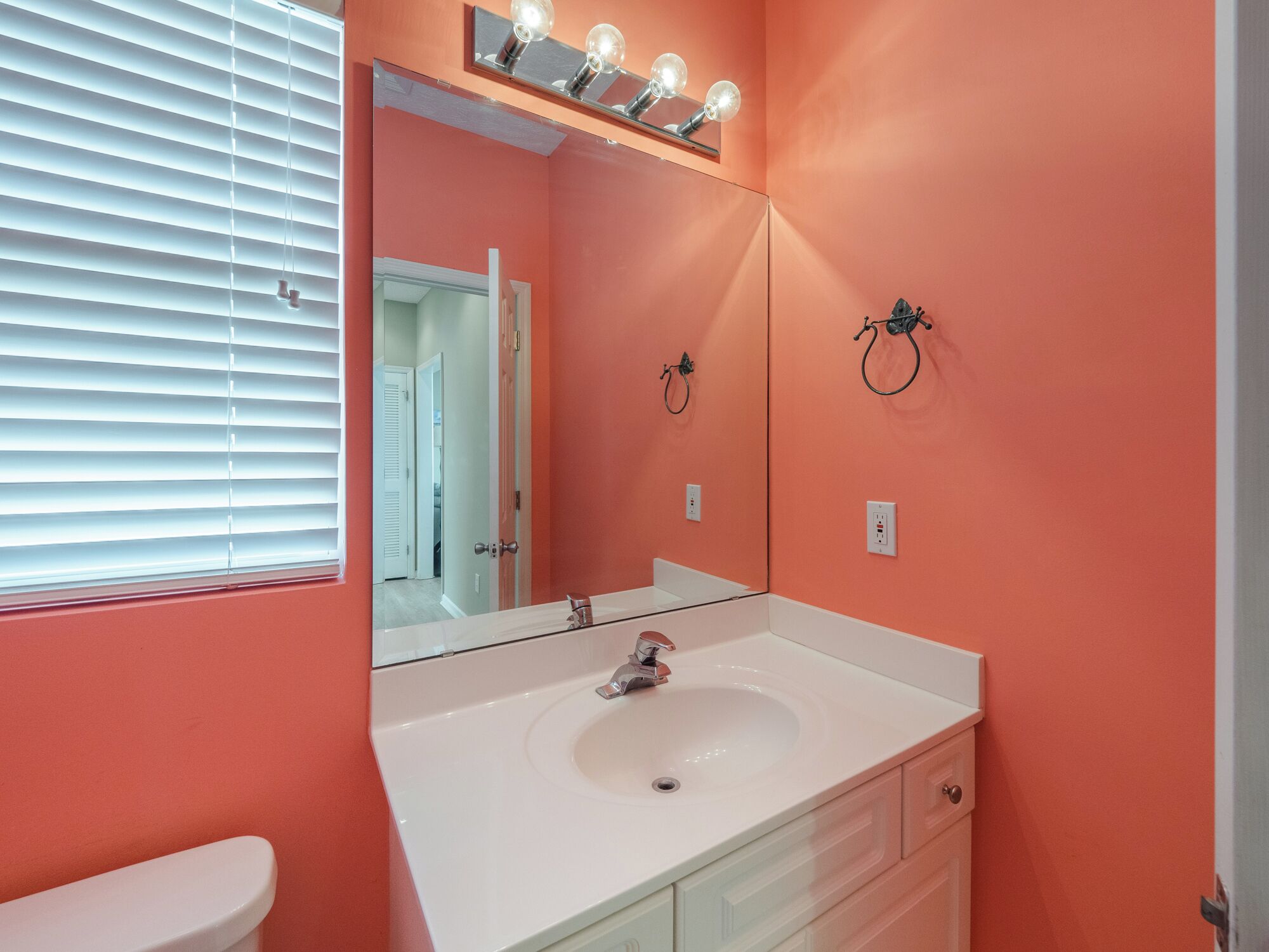 Een badkamer met een wit wastafel, een spiegel en een handdoekhouder aan de muur.