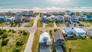 A coastal residential area with houses featuring front porches and a beach in the background. - Casa Capri by Topsail Realty (Holly Ridge)