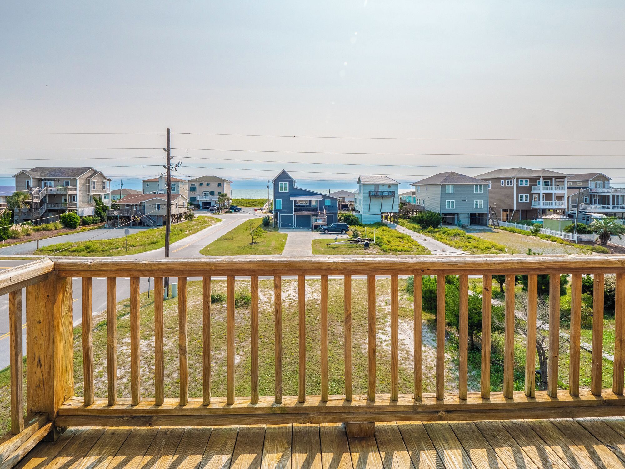 A residential area with houses, a road, and a beach in the background.