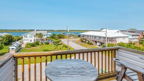 A wooden deck with a table and chairs, overlooking a marina with boats and houses. - Casa Capri by Topsail Realty (Holly Ridge)