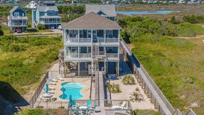 A multi-story beachfront property with a swimming pool, outdoor seating, and a wooden deck. - Shore Therapy by Topsail Realty (Sneads Ferry)